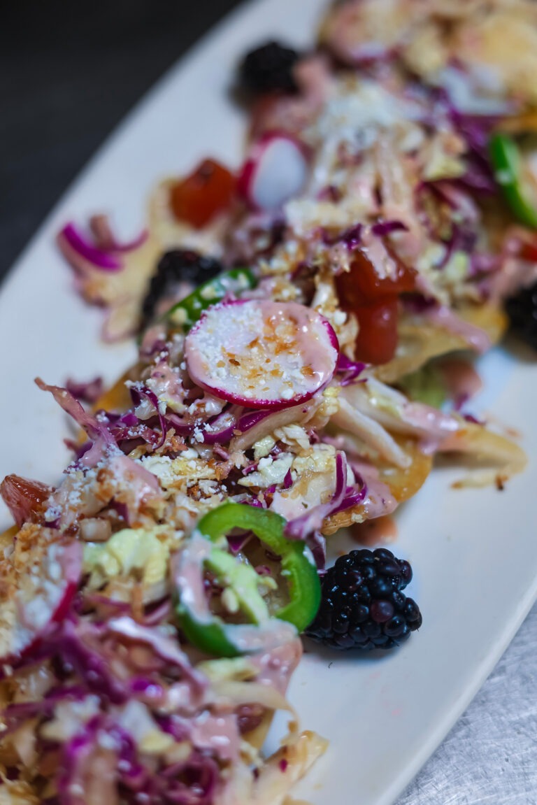 Poke Tuna Nachos - 6 oz of Ahi Tuna, Poke Sauce, Blackberry Aioli, Cabbage, Toasted Coconut, Cotija Cheese, Wasabi Avocado Creme, Jalapeno, Radish, Scallions, Blackberries, Gyoza Chips